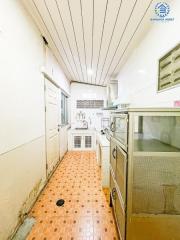 Narrow kitchen with white cabinetry and orange tiled flooring