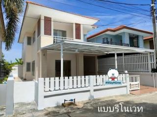 Two-story residential house with white fencing and carport