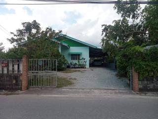 Single story residential home with a green facade and driveway