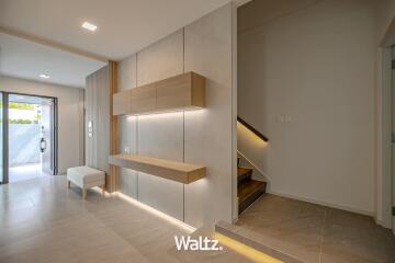 Modern interior of a home showing an entryway with staircase and kitchenette