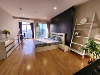 Spacious bedroom with wooden flooring and city view