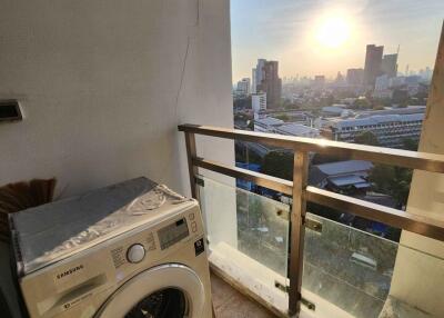 Balcony with a washing machine and cityscape view at sunset