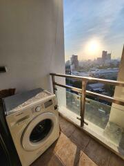 Balcony with a washing machine and cityscape view at sunset