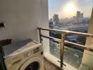 Balcony with a washing machine and cityscape view at sunset