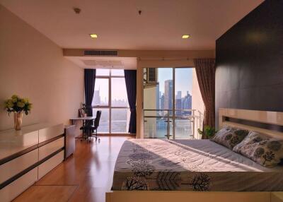 Spacious bedroom with modern design, ample natural light, city view, and office corner