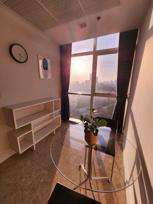 Cozy living area with large window and city view at sunset