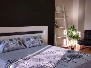 Contemporary bedroom with stylish bedding and a well-lit corner by a shelf