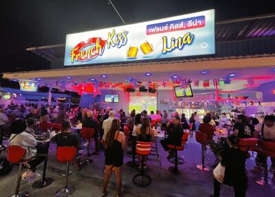 Busy outdoor restaurant at night with illuminated signage