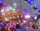 Lively outdoor street view at night with neon signs and people dining