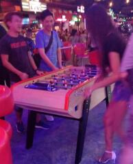 People enjoying a game of foosball in an entertainment area with vibrant ambiance
