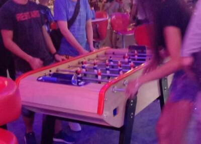 People enjoying a game of foosball in an entertainment area with vibrant ambiance