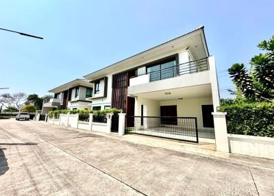 Modern two-story house with a white exterior, large windows, and a fenced-off lot