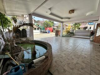 Spacious outdoor patio with tiled flooring and a small pond