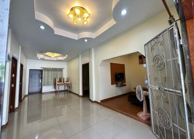 Spacious living room with modern design, featuring elegant ceiling decor and glossy floor tiles.