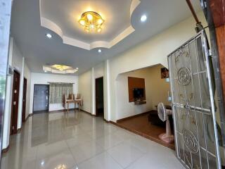 Spacious living room with modern design, featuring elegant ceiling decor and glossy floor tiles.