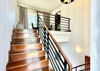 Elegant wooden staircase with a black handrail leading to an upper level of a home