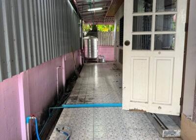 Tiled exterior corridor with a white door and metal roofing