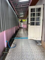 Tiled exterior corridor with a white door and metal roofing