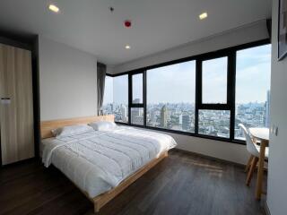 Modern bedroom with a large bed and expansive windows showcasing a city view