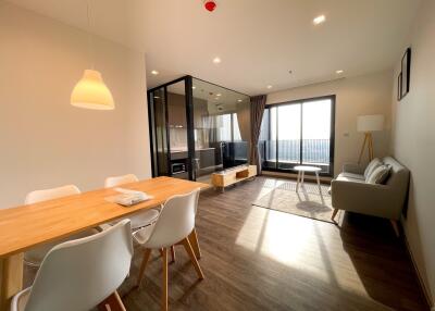 Spacious and well-lit living room with dining area and balcony access