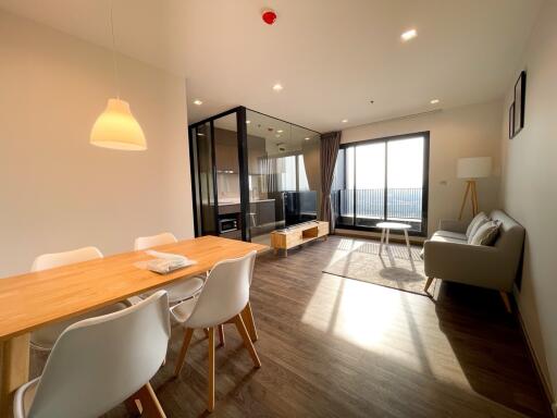 Spacious and well-lit living room with dining area and balcony access