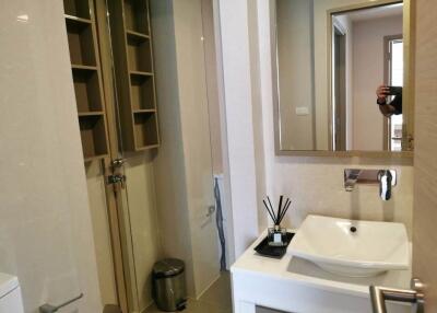 Modern bathroom interior with wooden shelving, glass shower, and white sink