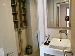 Modern bathroom interior with wooden shelving, glass shower, and white sink