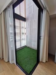 Compact balcony with artificial grass flooring and sliding glass doors