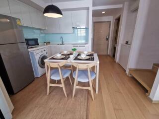 Modern kitchen with dining area, equipped with appliances and wooden flooring