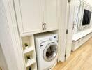 Compact utility room with a modern washing machine, white cabinetry, and green plant decor