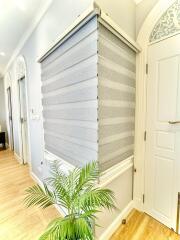 Elegant hallway with modern window shades, intricate wall moldings, and hardwood floors