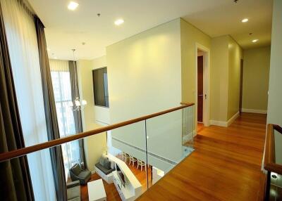 Spacious building interior showing a well-lit hallway with wooden flooring and glass panel railings