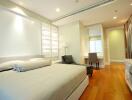 Spacious bedroom with modern design, hardwood floors, and ample lighting