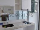 Modern kitchen interior with white cabinetry and stainless steel sink