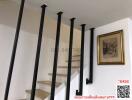 Wide staircase with black handrails leading to the upper level of a home, with a framed artwork on the wall