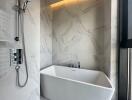 Modern bathroom with white freestanding bathtub and marble walls