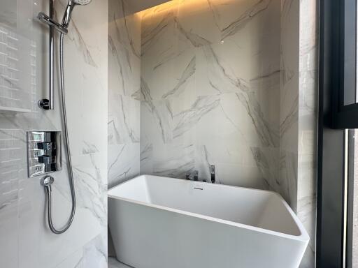 Modern bathroom with white freestanding bathtub and marble walls