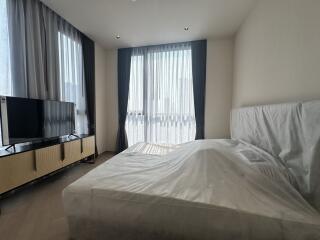 Spacious bedroom with modern design, featuring large windows, a double bed, and a flat-screen TV