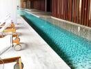 Modern indoor swimming pool with wooden slatted design and lounge chairs