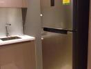 Compact modern kitchen with stainless steel refrigerator