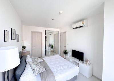 Modern bright bedroom with a comfortable bed, air conditioning, and flat-screen TV