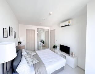 Modern bright bedroom with a comfortable bed, air conditioning, and flat-screen TV