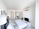 Modern bright bedroom with a comfortable bed, air conditioning, and flat-screen TV