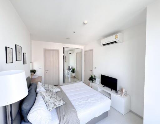 Modern bright bedroom with a comfortable bed, air conditioning, and flat-screen TV