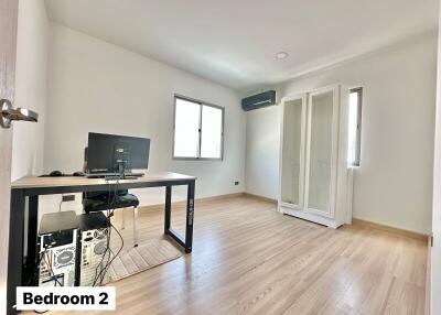 Spacious bedroom with computer desk and wooden flooring