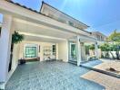 Spacious paved patio area of a residential house with open sliding doors and greenery