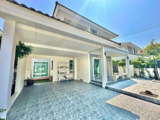 Spacious paved patio area of a residential house with open sliding doors and greenery