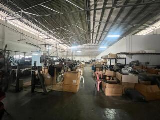 Interior view of a spacious industrial warehouse with boxes and machinery