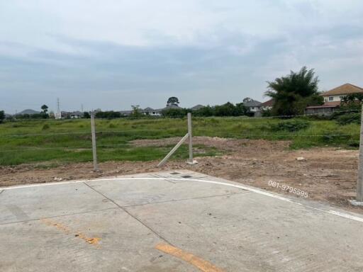 Vacant plot of land ready for construction with a clear sky and neighboring buildings in the distance