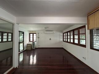 Spacious and empty living room with hardwood floors and large windows